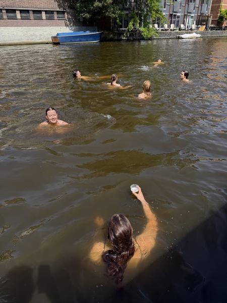 A group of friends enjoys a refreshing swim in the Nieuwe Prinsengracht canal in Weesperbuurt, Amsterdam on a bright, sunny day